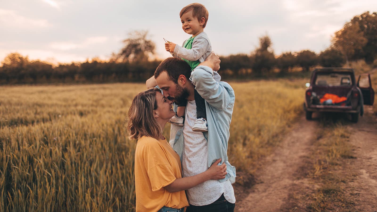 Young son on fathers shoulders while hugging the mother