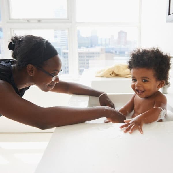 Woman playing with kid in bathtub.