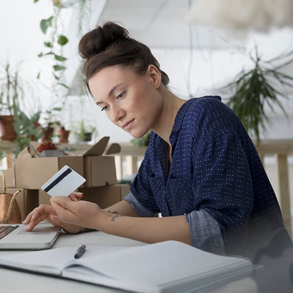 Woman holding her credit card purchasing something on her laptop.