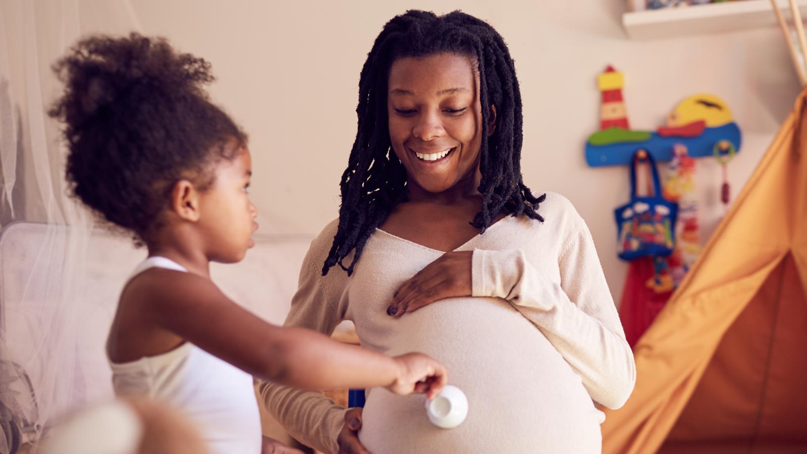 Pregnant mom playing with her toddler at home.