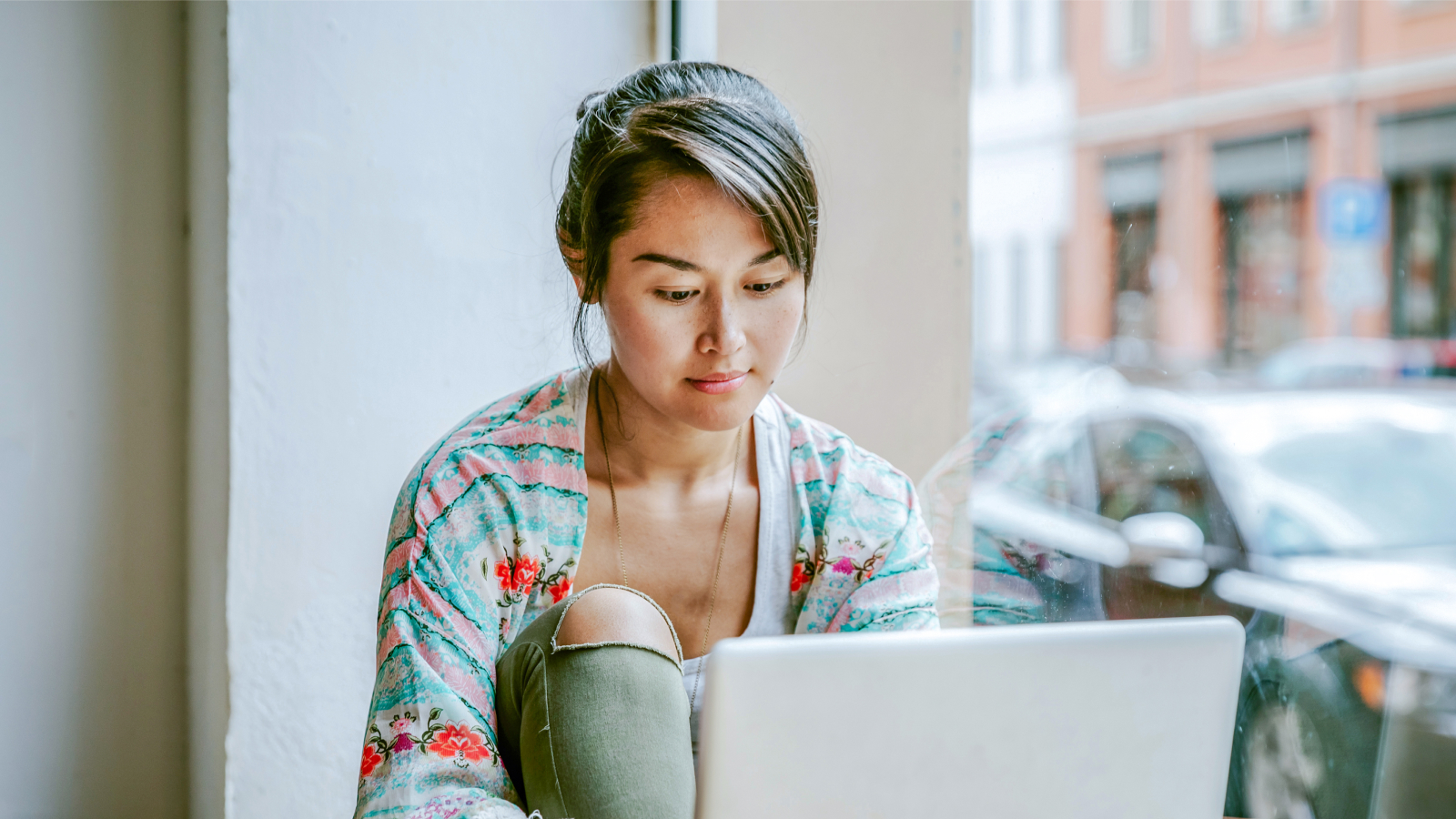Young woman working on laptop in cafe window