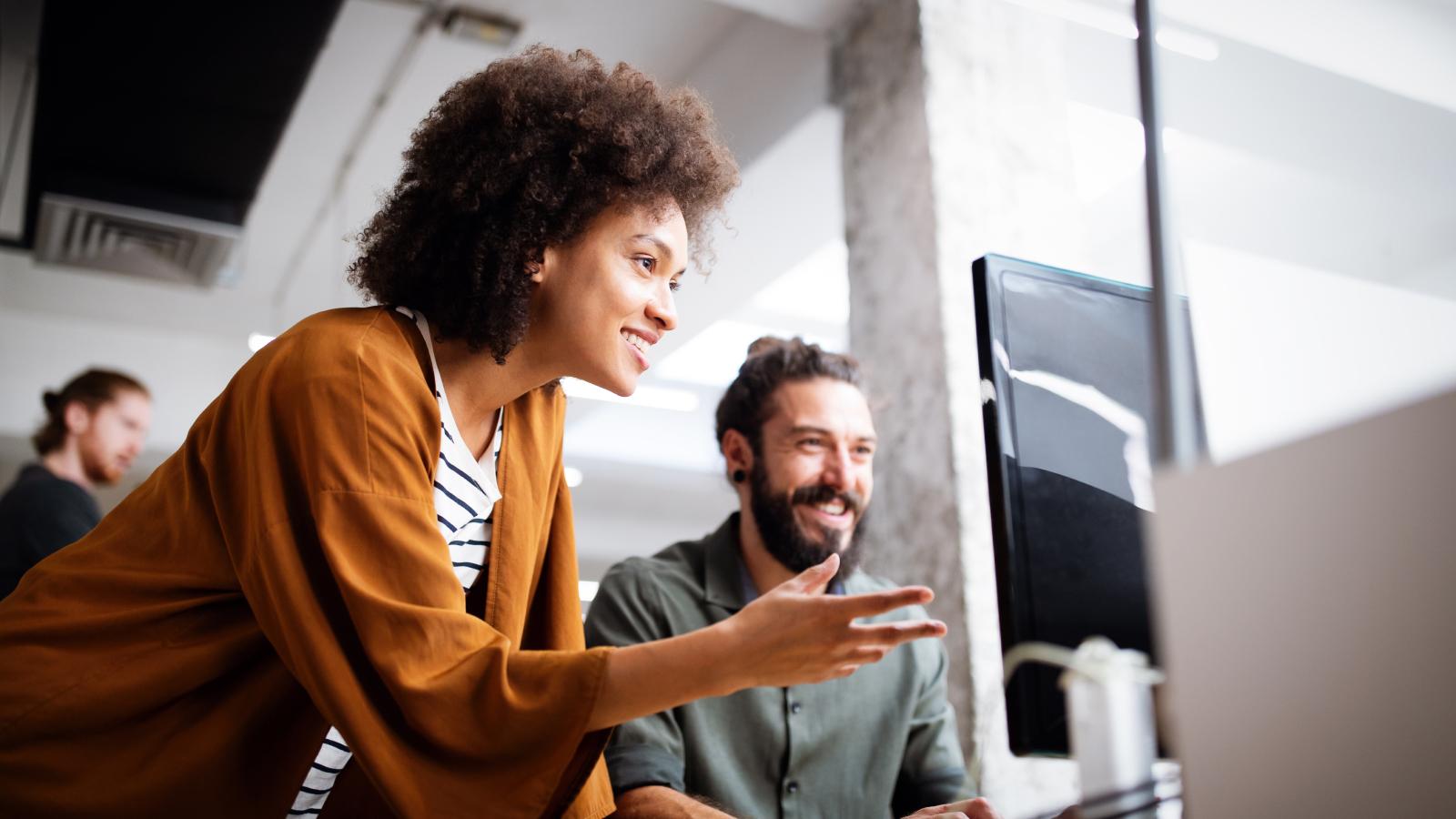 Employees happily looking at desktop together