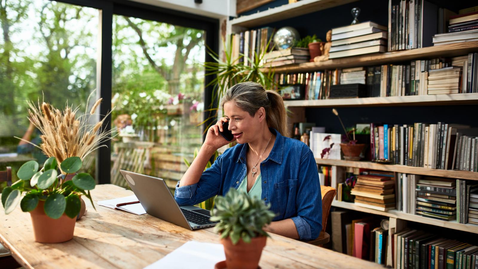 Businesswoman using laptop talking on phone